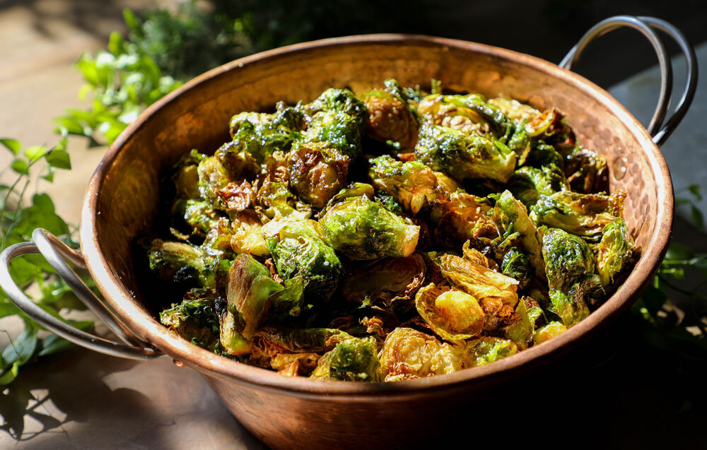 Caramelized brussels sprouts served in a bronze bowl at Il Mercato, Joel Catering's premier New Orleans event venue.