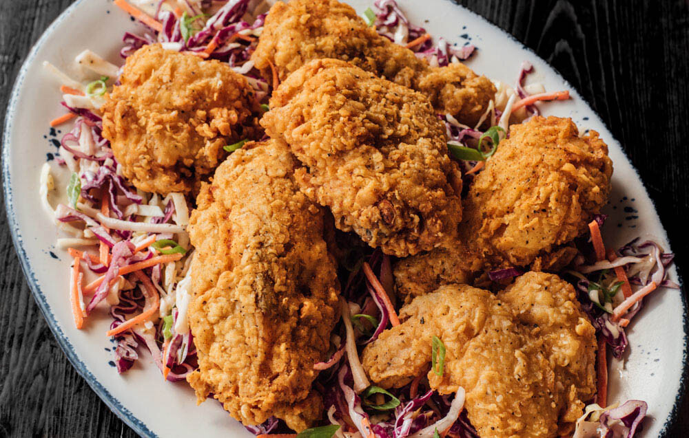 Joel Catering's signature secret-recipe battered fried chicken, elegantly paired with a gourmet slaw salad, showcasing their premium catering dishes in New Orleans.