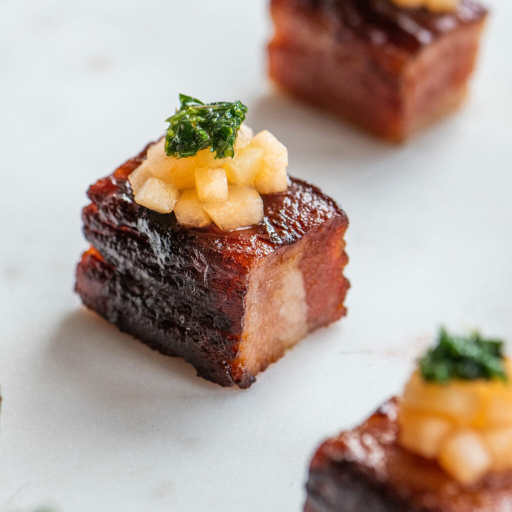 Crispy pork belly with mango slaw on top served as an appetizer at an event in New Orleans